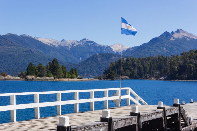 La bandera argentina ondeando orgullosa sobre un fondo de majestuosas montañas